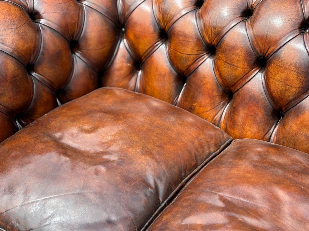 A nineteenth-century three-seater Chesterfield sofa upholstered in deep buttoned chestnut brown leather with brass stud detailing along the rolled arms. View IV