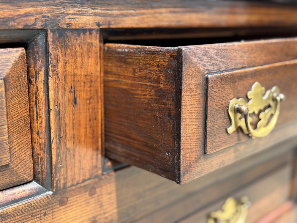 An 18th-century George II solid oak dresser base featuring multiple drawers, panelled cupboard doors, and brass drop handles. View IX