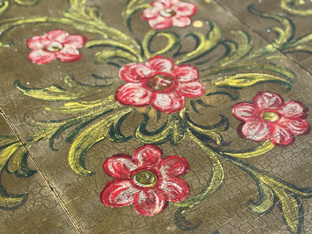 An early 20th-century Italian oval drop-leaf table painted in olive green with hand-painted red floral and green foliage motifs across the top surface. View V