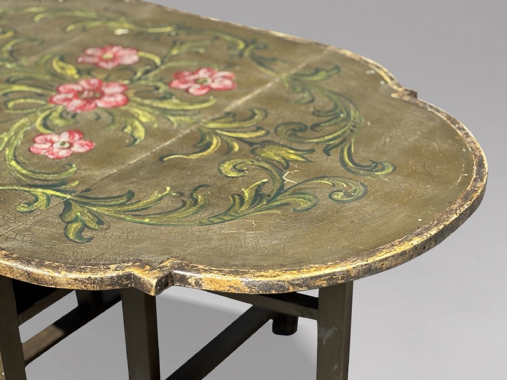An early 20th-century Italian oval drop-leaf table painted in olive green with hand-painted red floral and green foliage motifs across the top surface. View IX