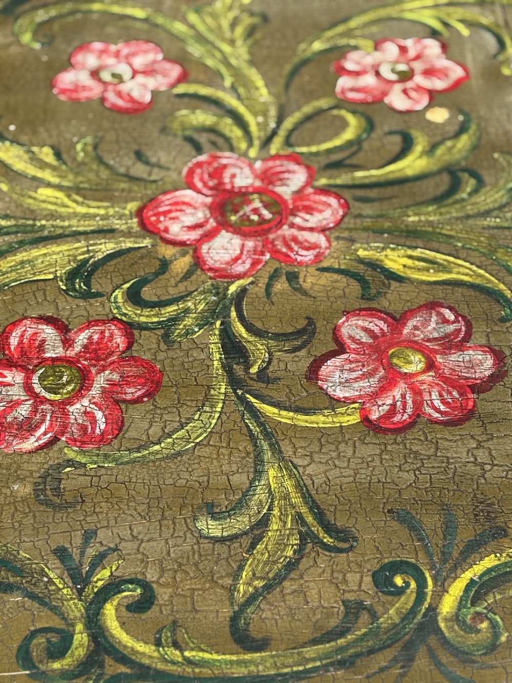 An early 20th-century Italian oval drop-leaf table painted in olive green with hand-painted red floral and green foliage motifs across the top surface. View X