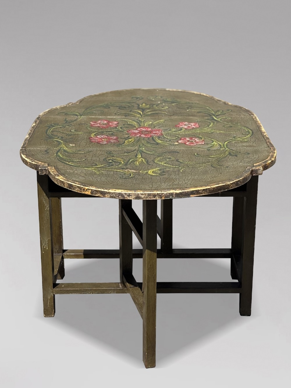 An early 20th-century Italian oval drop-leaf table painted in olive green with hand-painted red floral and green foliage motifs across the top surface. View XI