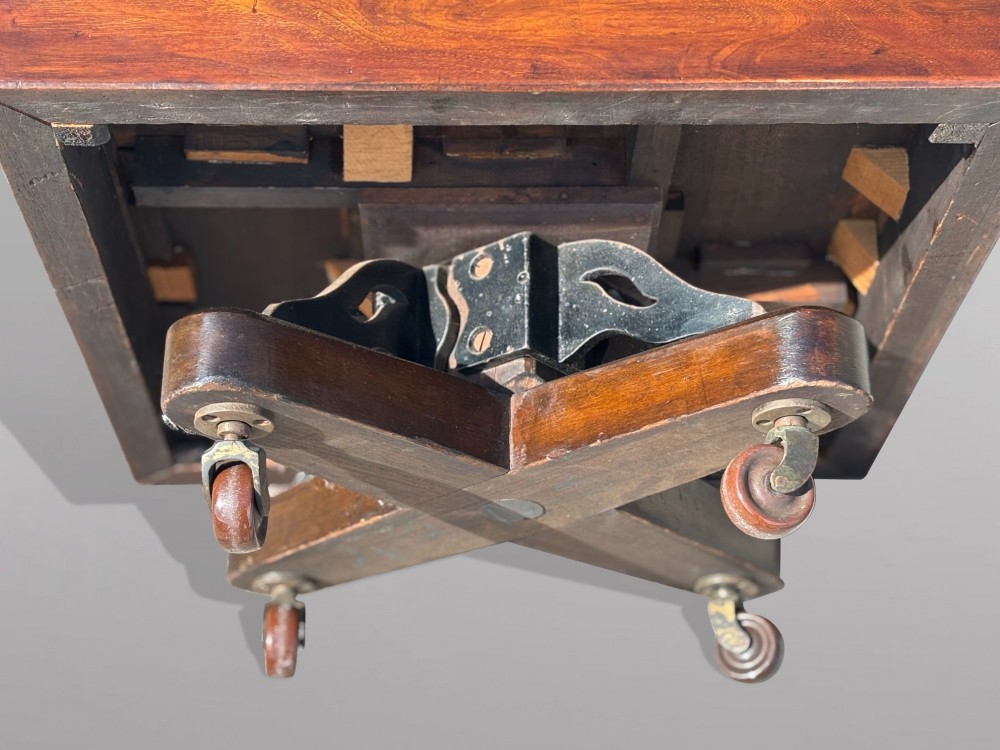 A 19th-century Victorian dark mahogany revolving bookcase featuring two slatted tiers on a central rotating base with castors. View IV