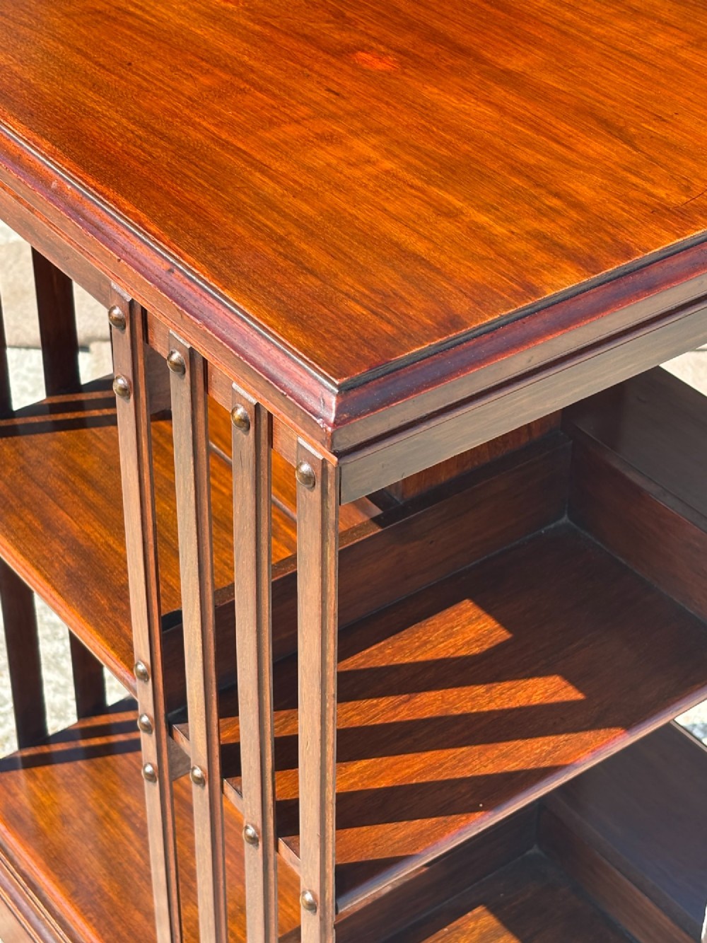 A 19th-century Victorian dark mahogany revolving bookcase featuring two slatted tiers on a central rotating base with castors. View VI