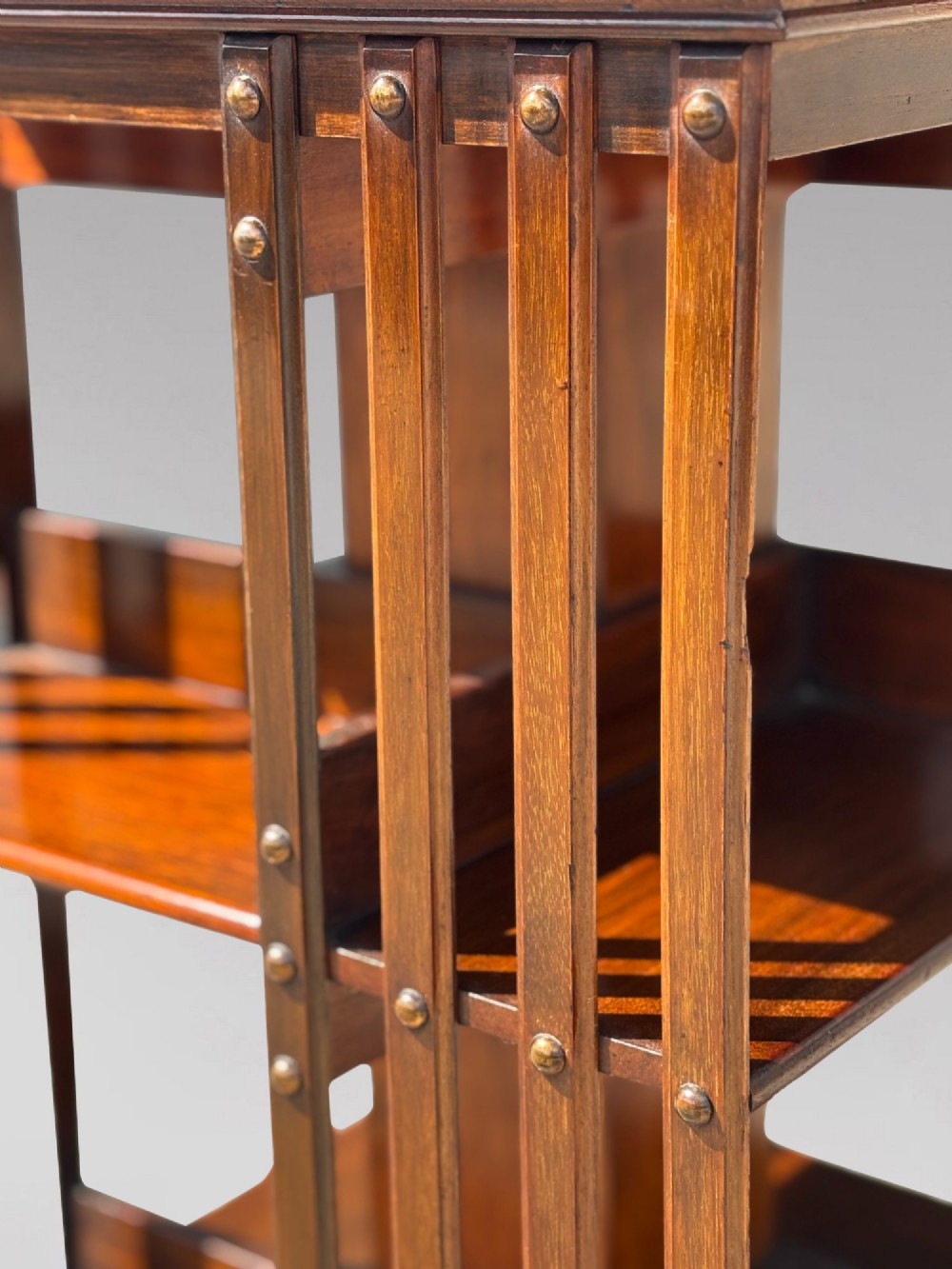 A 19th-century Victorian dark mahogany revolving bookcase featuring two slatted tiers on a central rotating base with castors. View VIII