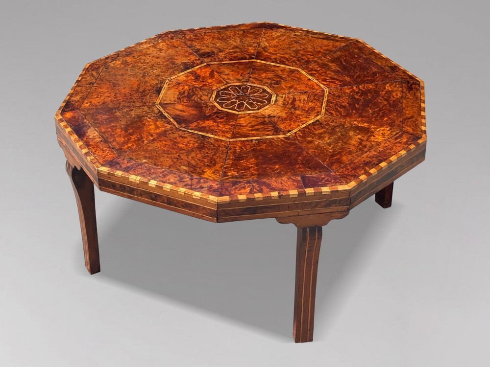 An octagonal 19th-century burr yew wood coffee table featuring radiating veneer panels, a central inlaid star motif, and a checkered border.