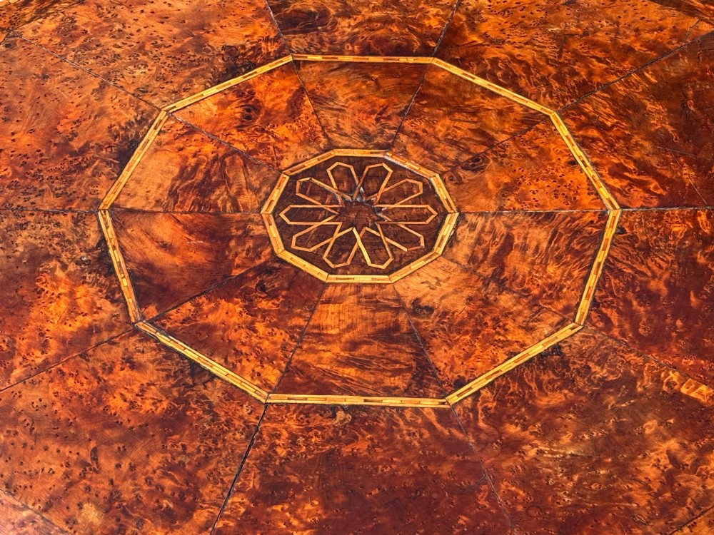 An octagonal 19th-century burr yew wood coffee table featuring radiating veneer panels, a central inlaid star motif, and a checkered border. View IV