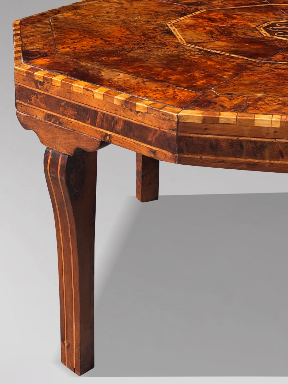 An octagonal 19th-century burr yew wood coffee table featuring radiating veneer panels, a central inlaid star motif, and a checkered border. View VI