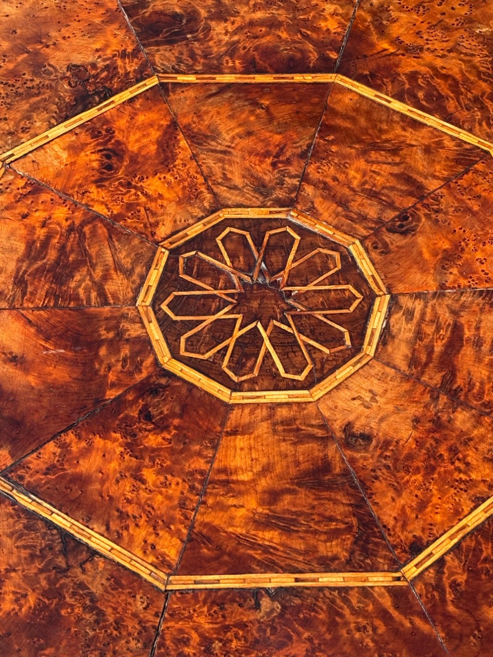 An octagonal 19th-century burr yew wood coffee table featuring radiating veneer panels, a central inlaid star motif, and a checkered border. View VII