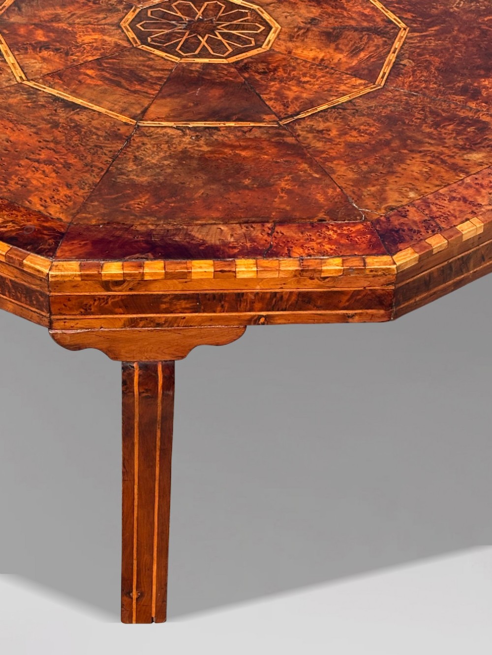 An octagonal 19th-century burr yew wood coffee table featuring radiating veneer panels, a central inlaid star motif, and a checkered border. View IX