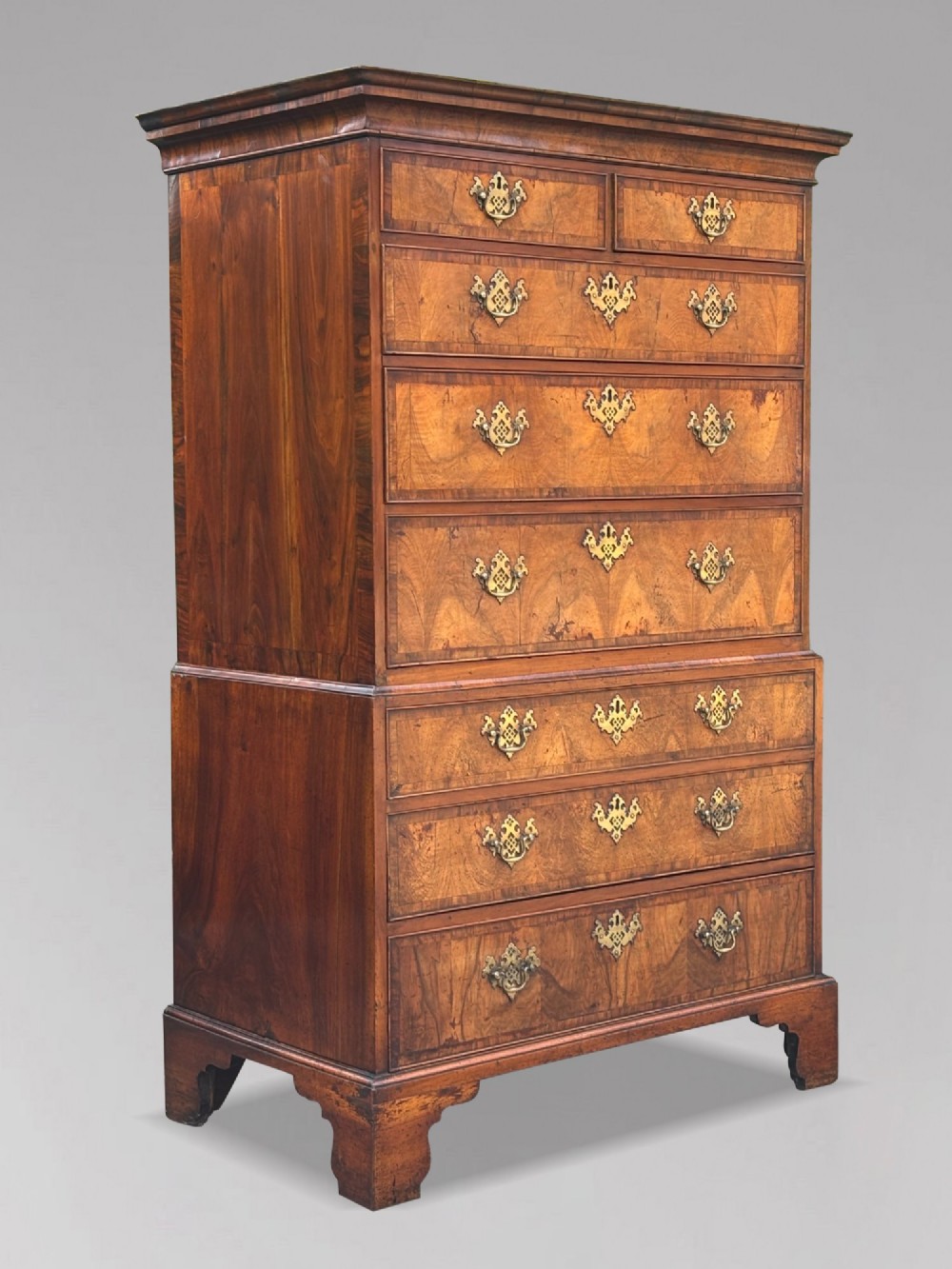 An eighteenth-century George II walnut chest on chest featuring two short over six long graduated drawers with decorative brass handles, keyhole escutcheons, and bracket feet. View II