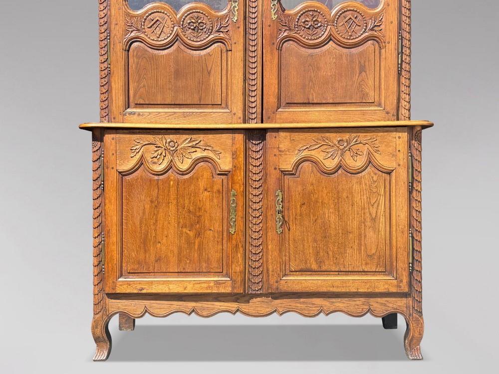 An 18th-century carved oak French buffet deux corps featuring upper glazed doors lined with fabric above a panelled lower cabinet with relief carvings. View V