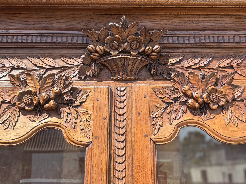 An 18th-century carved oak French buffet deux corps featuring upper glazed doors lined with fabric above a panelled lower cabinet with relief carvings. View VI