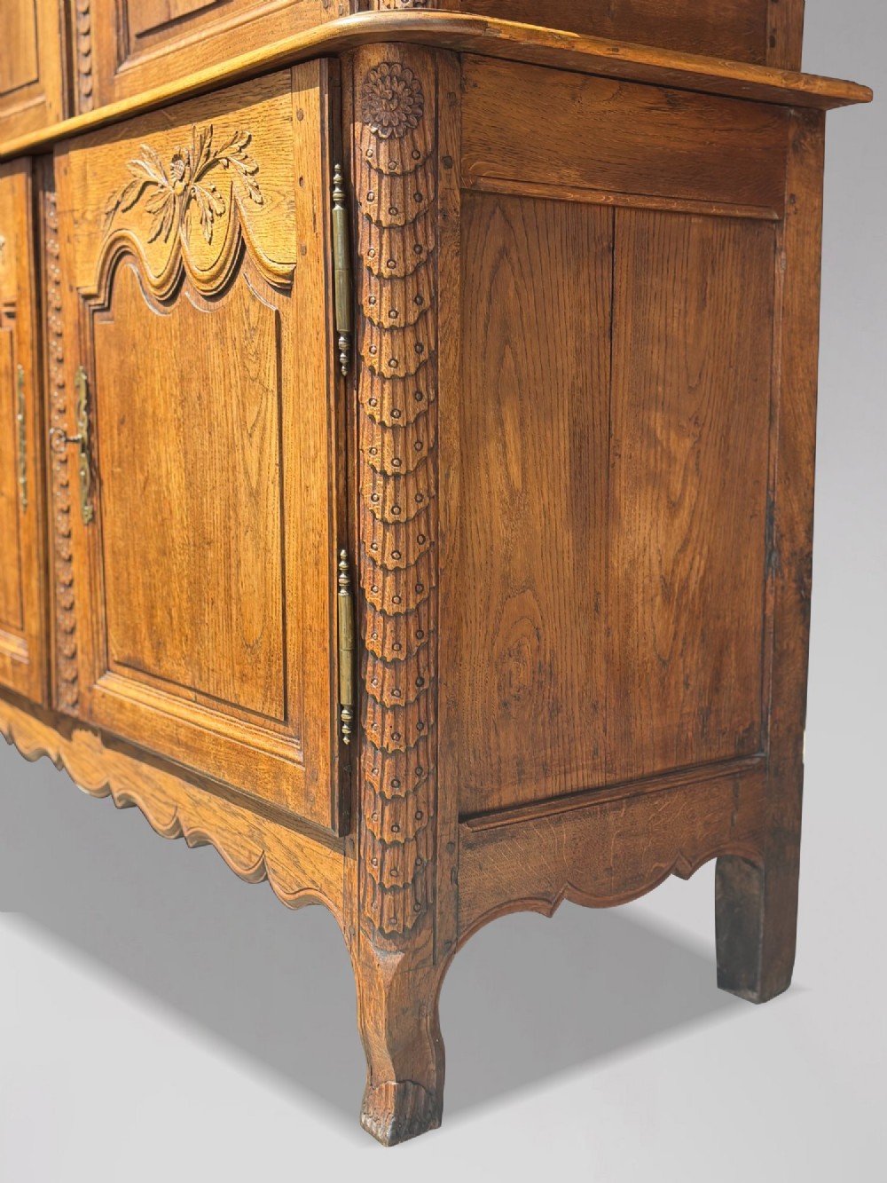 An 18th-century carved oak French buffet deux corps featuring upper glazed doors lined with fabric above a panelled lower cabinet with relief carvings. View XII