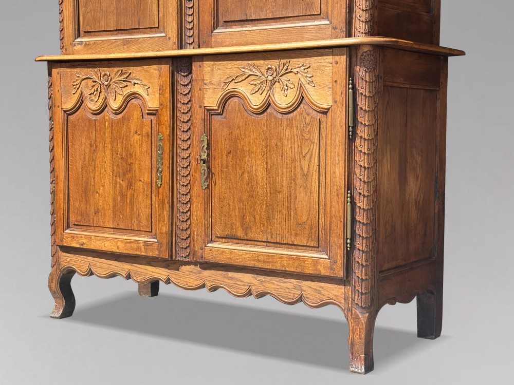 An 18th-century carved oak French buffet deux corps featuring upper glazed doors lined with fabric above a panelled lower cabinet with relief carvings. View XIII