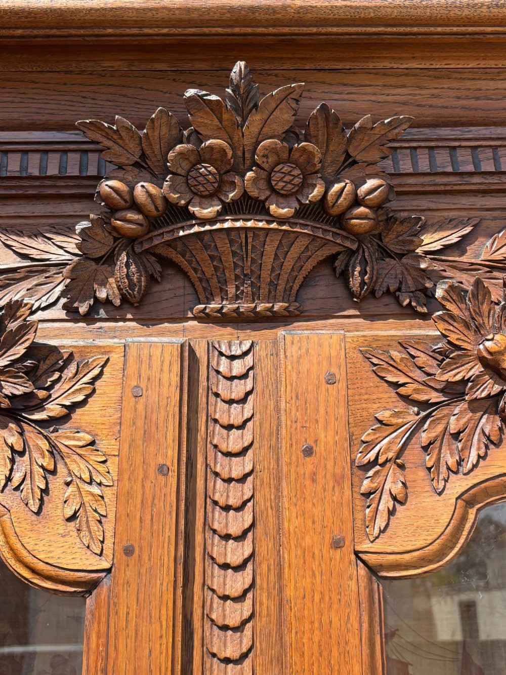 An 18th-century carved oak French buffet deux corps featuring upper glazed doors lined with fabric above a panelled lower cabinet with relief carvings. View XV