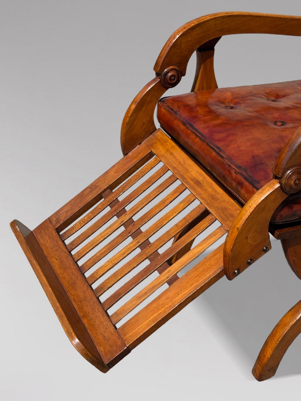 A pair of 19th-century Victorian walnut reclining armchairs featuring slatted backrests, extendable footrests, curved X-frame bases, and brown leather seat cushions. View VIII
