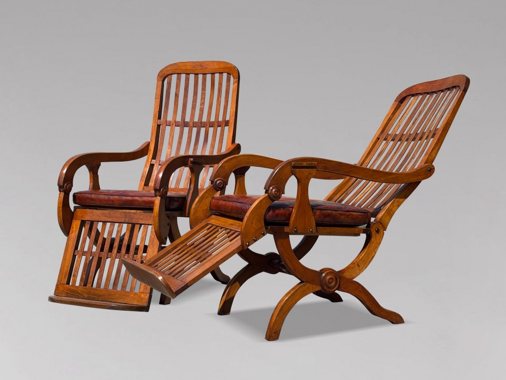 A pair of 19th-century Victorian walnut reclining armchairs featuring slatted backrests, extendable footrests, curved X-frame bases, and brown leather seat cushions. View XIII