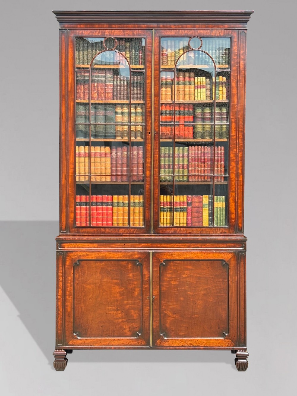 An eighteenth-century George III tall mahogany bookcase featuring two upper astragal glazed doors, lower flame-veneered cabinet doors, and a moulded cornice. View II