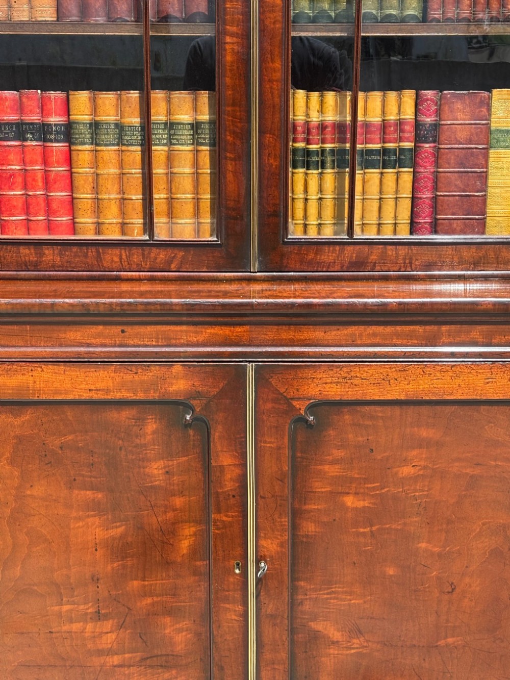 An eighteenth-century George III tall mahogany bookcase featuring two upper astragal glazed doors, lower flame-veneered cabinet doors, and a moulded cornice. View IV