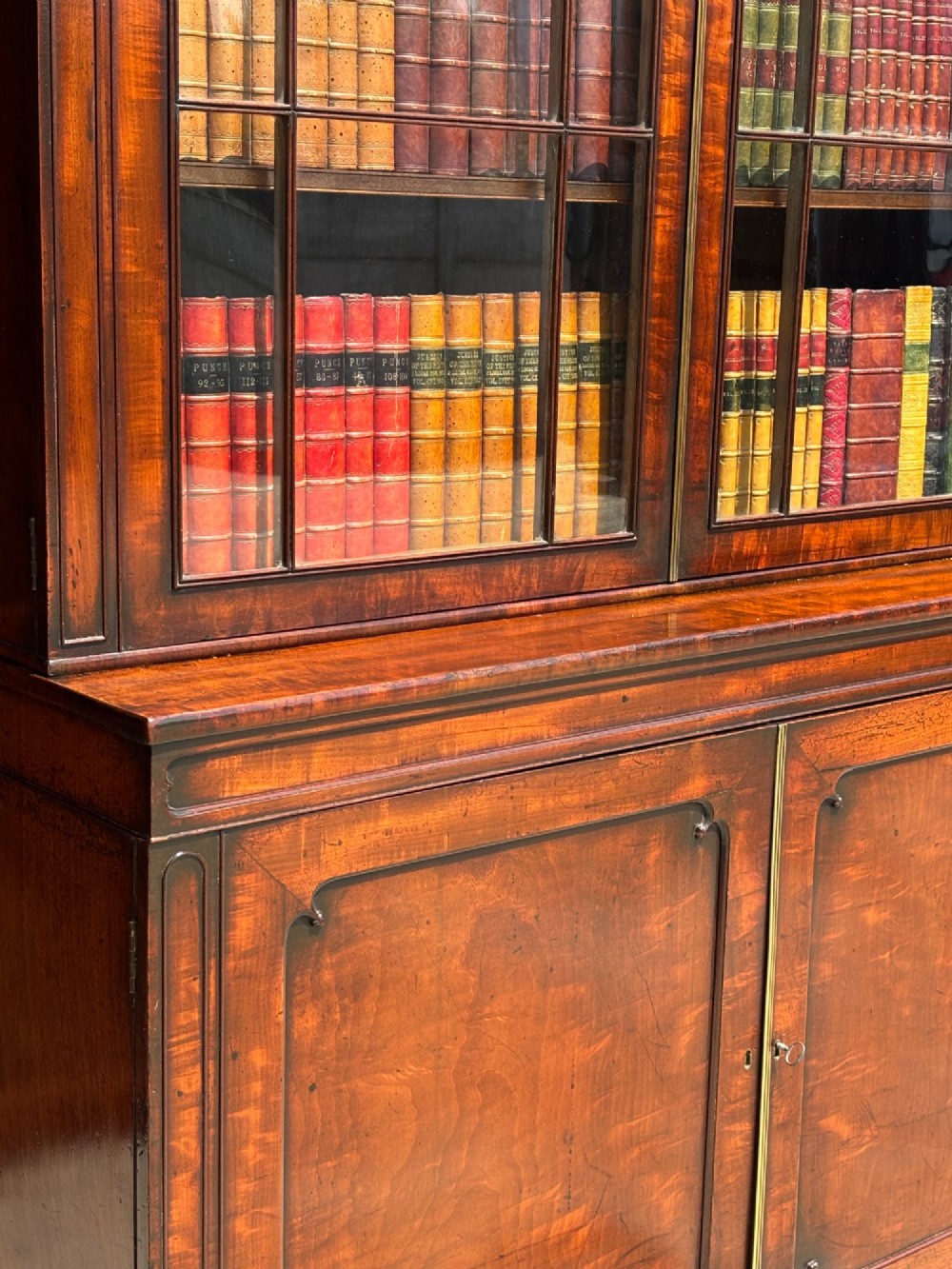 An eighteenth-century George III tall mahogany bookcase featuring two upper astragal glazed doors, lower flame-veneered cabinet doors, and a moulded cornice. View V