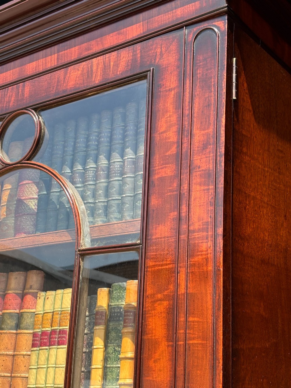 An eighteenth-century George III tall mahogany bookcase featuring two upper astragal glazed doors, lower flame-veneered cabinet doors, and a moulded cornice. View VI