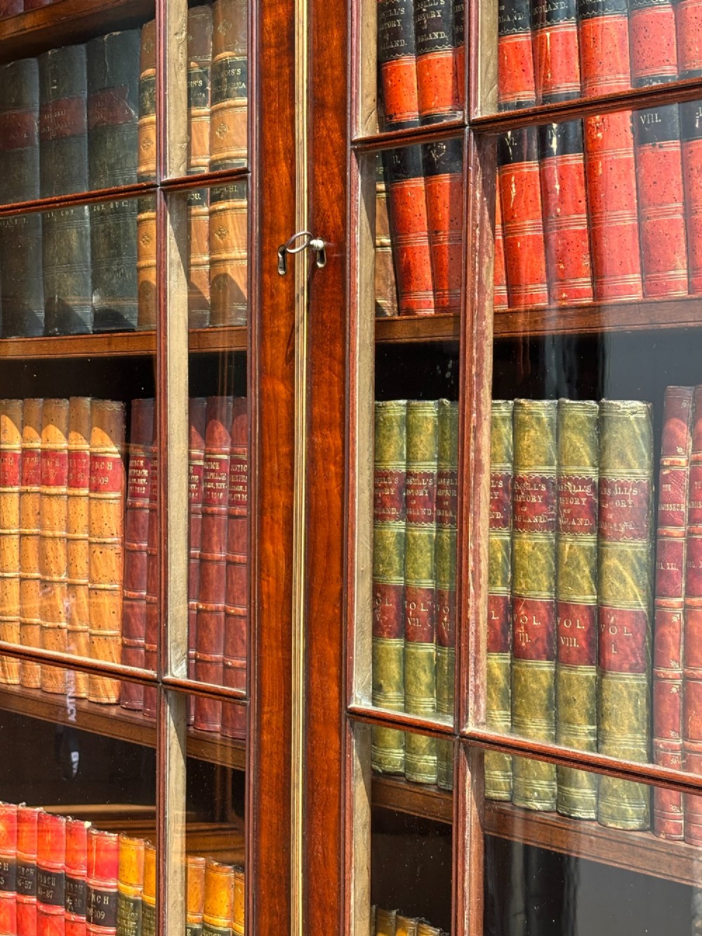An eighteenth-century George III tall mahogany bookcase featuring two upper astragal glazed doors, lower flame-veneered cabinet doors, and a moulded cornice. View VII