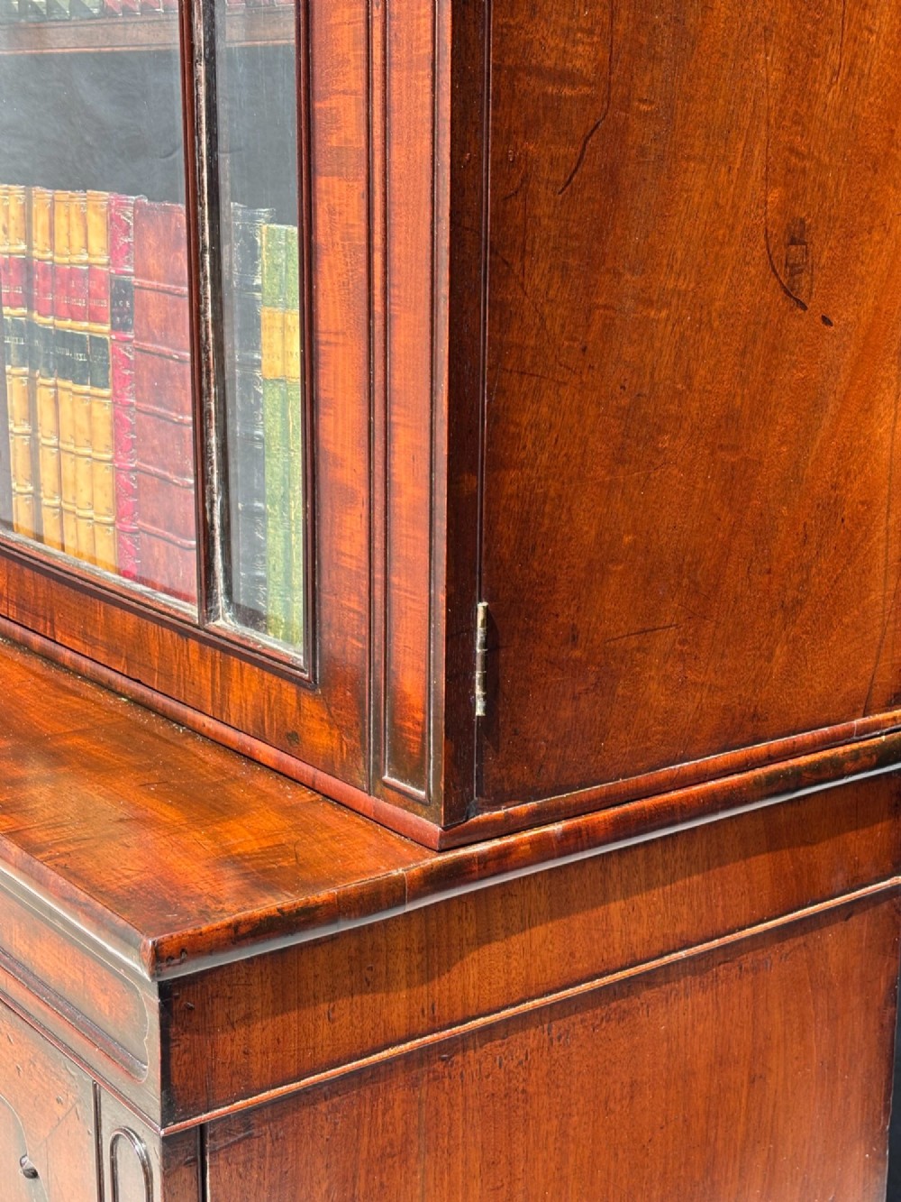 An eighteenth-century George III tall mahogany bookcase featuring two upper astragal glazed doors, lower flame-veneered cabinet doors, and a moulded cornice. View XV