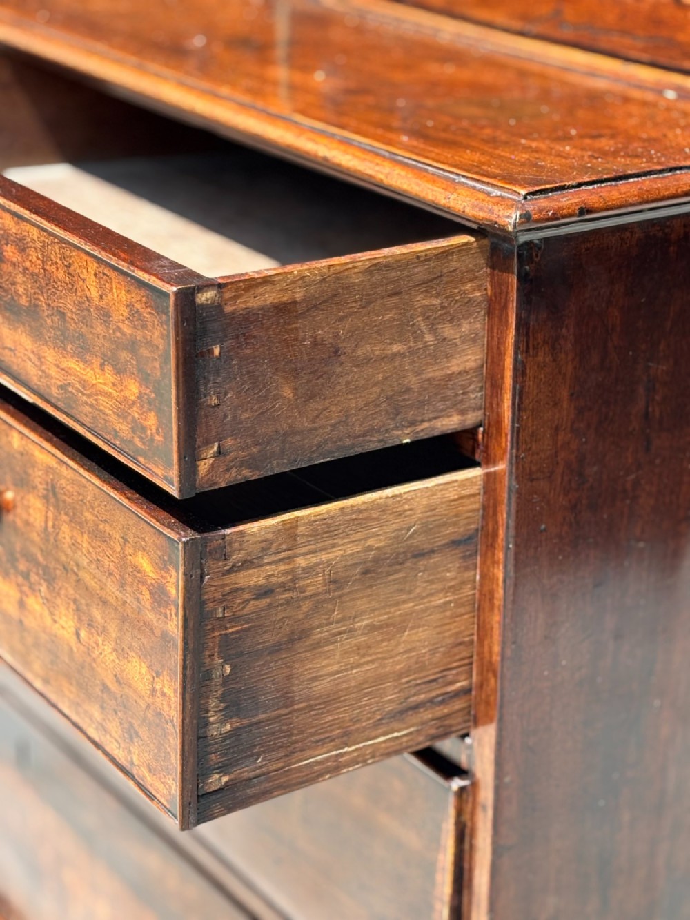An 18th-century George III mahogany bookcase on chest featuring a broken pediment, carved frieze, geometric astragal glazed doors, and four lower drawers with brass handles. View VII