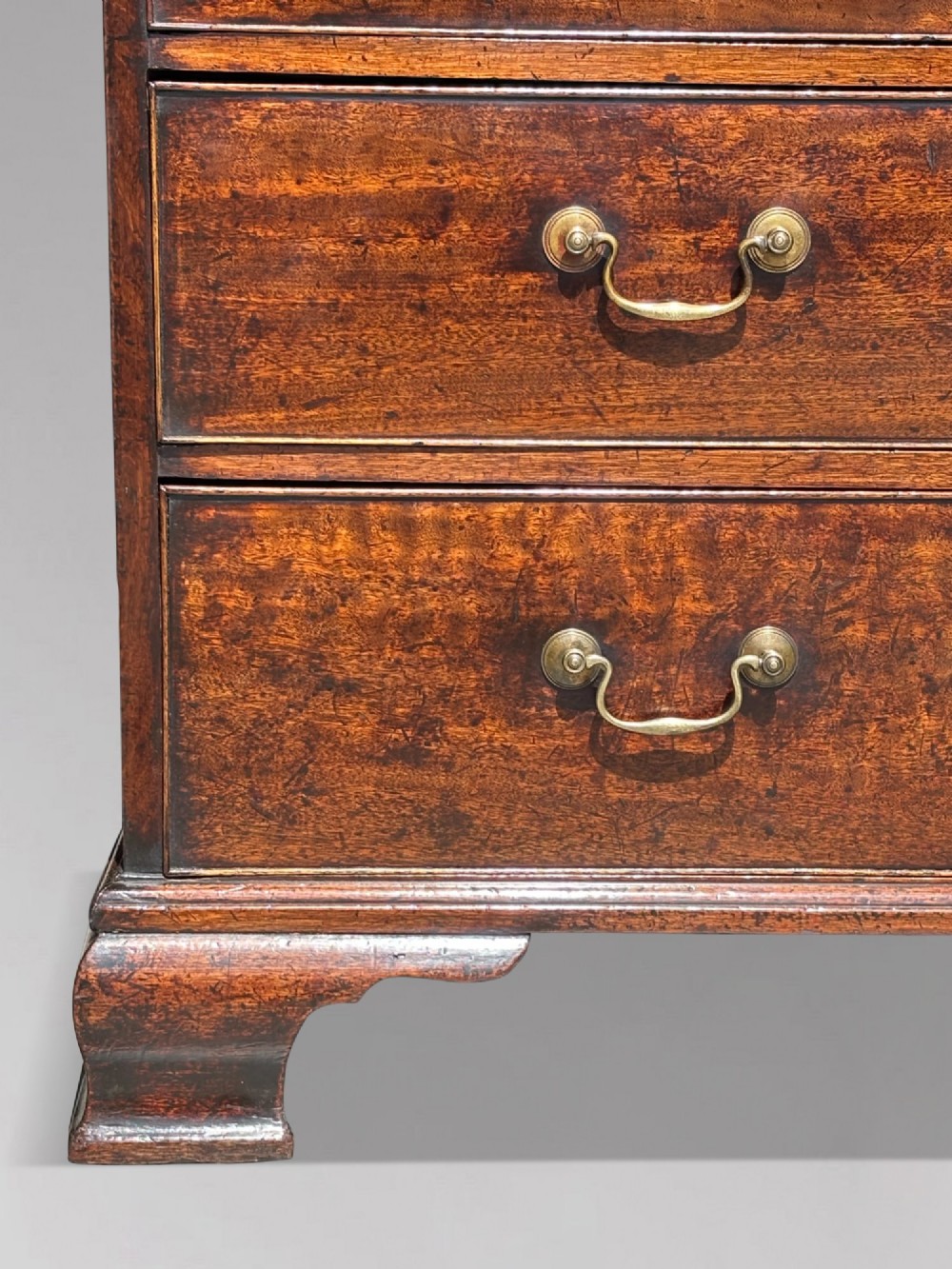 An 18th-century George III mahogany bookcase on chest featuring a broken pediment, carved frieze, geometric astragal glazed doors, and four lower drawers with brass handles. View VIII