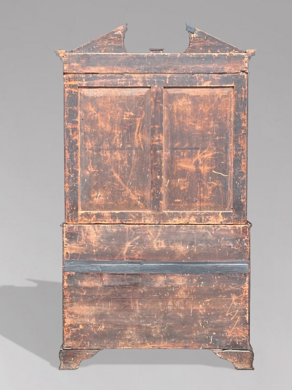 An 18th-century George III mahogany bookcase on chest featuring a broken pediment, carved frieze, geometric astragal glazed doors, and four lower drawers with brass handles. View IX