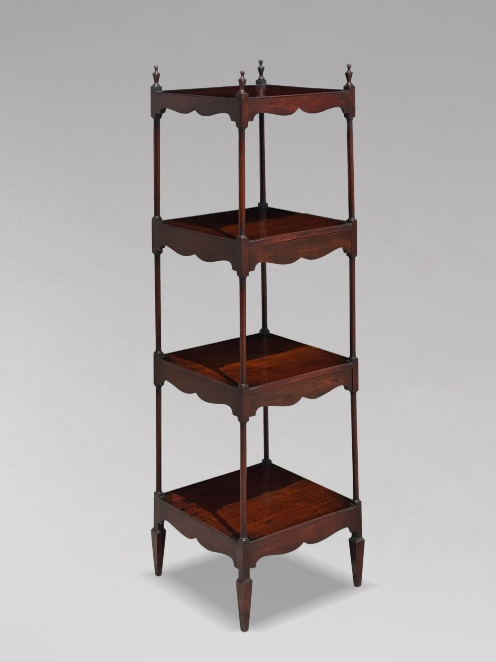 A four-tiered George III mahogany whatnot featuring slender corner supports, turned finials, scalloped aprons, and square tapered legs. View III