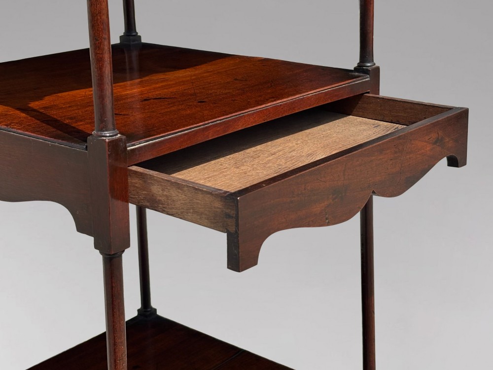 A four-tiered George III mahogany whatnot featuring slender corner supports, turned finials, scalloped aprons, and square tapered legs. View VI