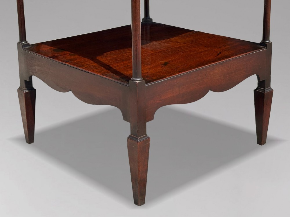 A four-tiered George III mahogany whatnot featuring slender corner supports, turned finials, scalloped aprons, and square tapered legs. View VII