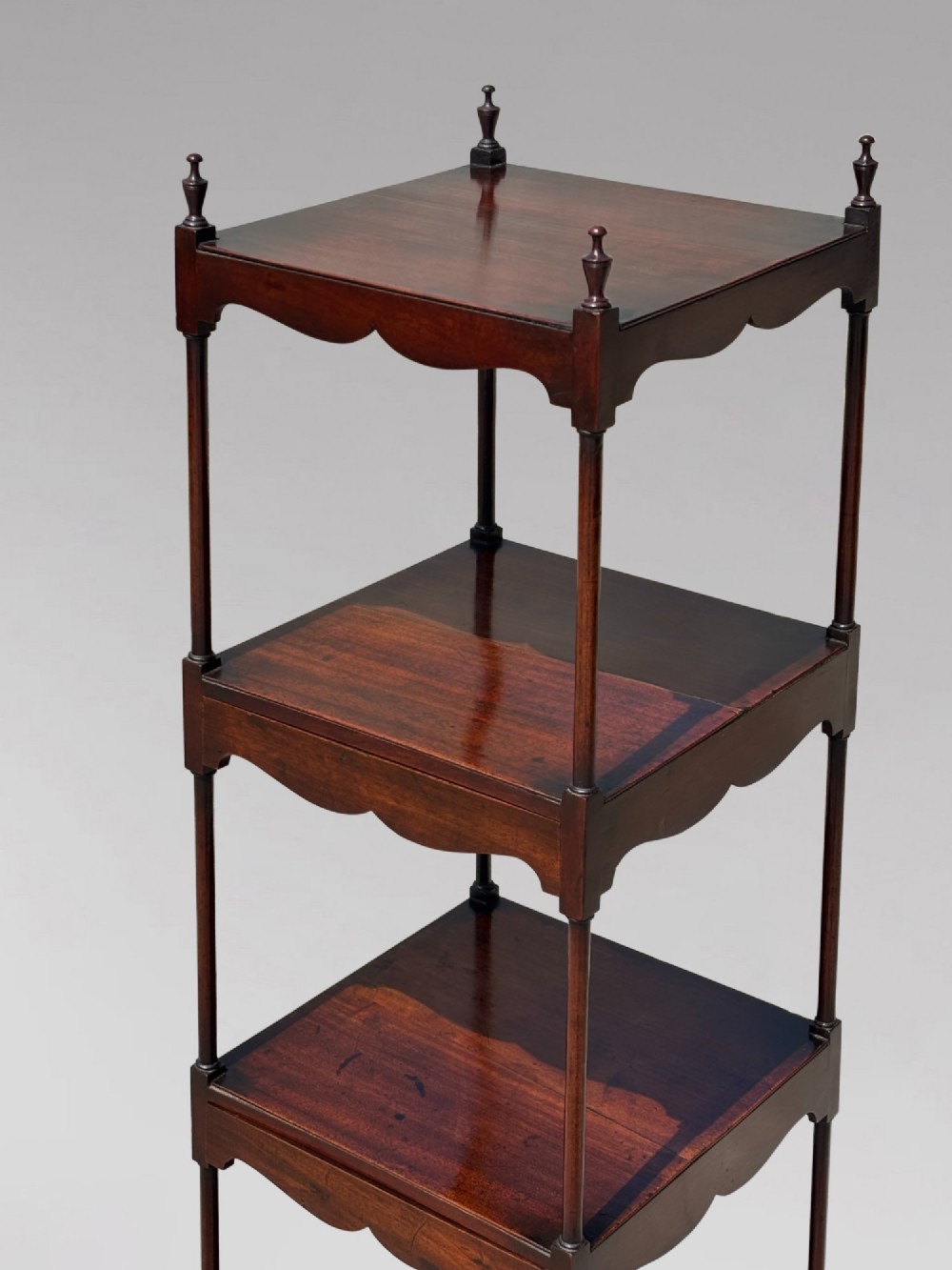 A four-tiered George III mahogany whatnot featuring slender corner supports, turned finials, scalloped aprons, and square tapered legs. View IX