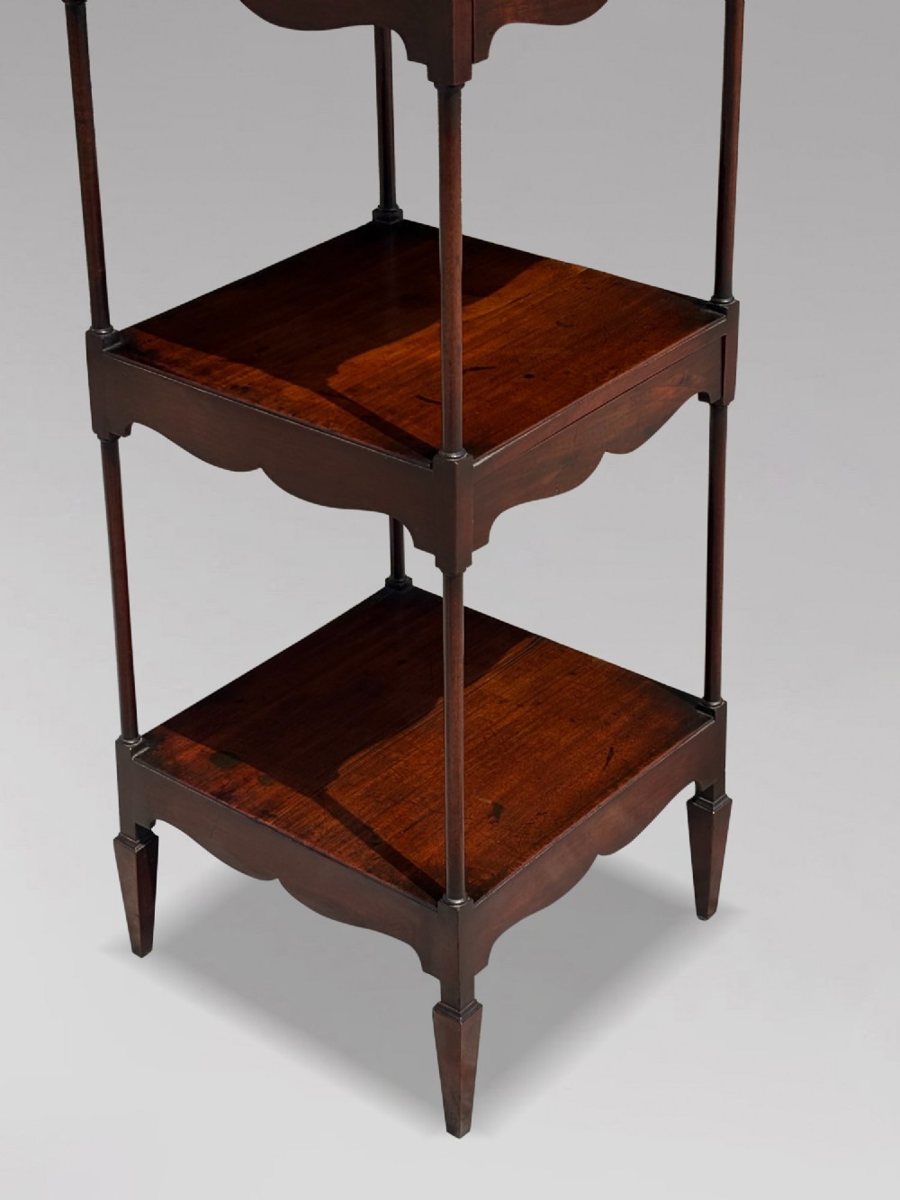 A four-tiered George III mahogany whatnot featuring slender corner supports, turned finials, scalloped aprons, and square tapered legs. View X