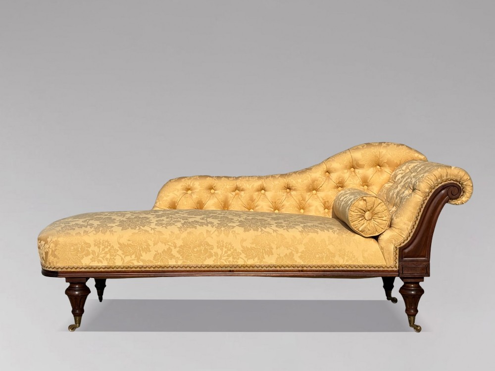 A 19th-century Regency mahogany chaise longue upholstered in yellow damask fabric with deep buttoning, a bolster cushion, and turned legs on brass castors. View II