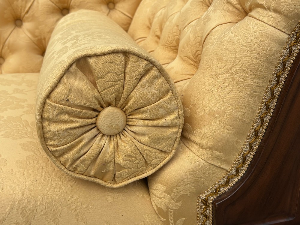 A 19th-century Regency mahogany chaise longue upholstered in yellow damask fabric with deep buttoning, a bolster cushion, and turned legs on brass castors. View VI