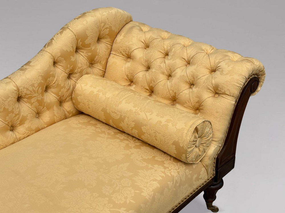 A 19th-century Regency mahogany chaise longue upholstered in yellow damask fabric with deep buttoning, a bolster cushion, and turned legs on brass castors. View VII