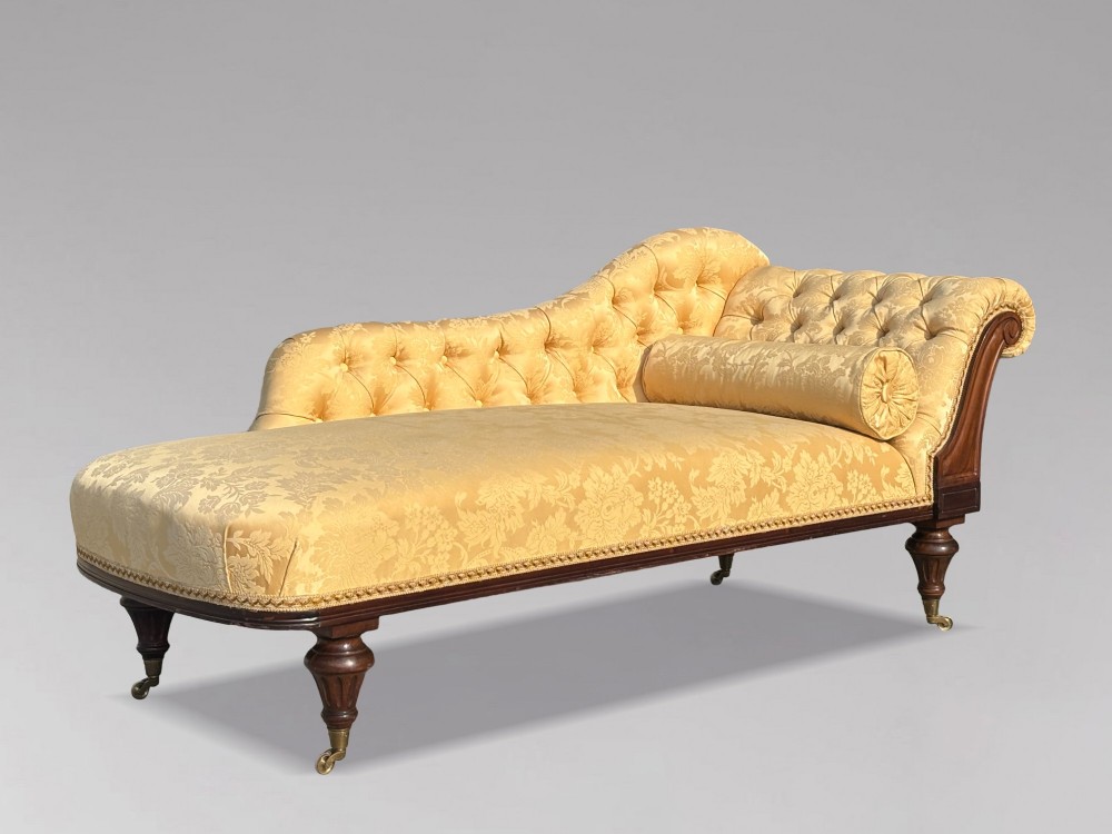 A 19th-century Regency mahogany chaise longue upholstered in yellow damask fabric with deep buttoning, a bolster cushion, and turned legs on brass castors. View IX