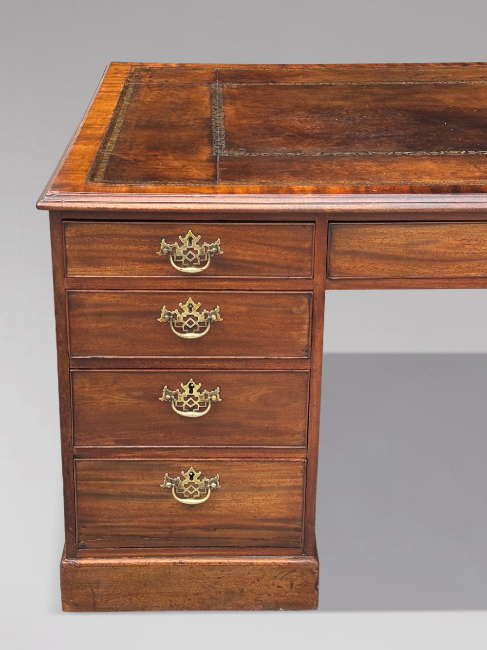 An 18th-century George III mahogany partners desk featuring an inset leather writing surface, brass swan-neck handles, and twin pedestals with stacked drawers. View III