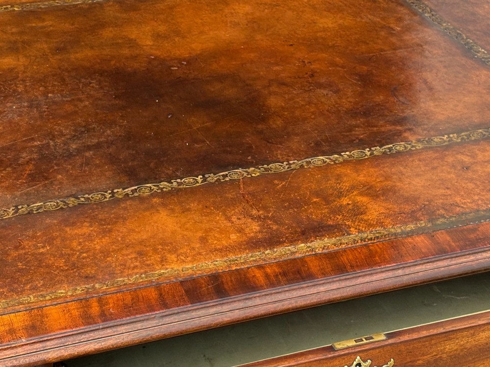 An 18th-century George III mahogany partners desk featuring an inset leather writing surface, brass swan-neck handles, and twin pedestals with stacked drawers. View VI