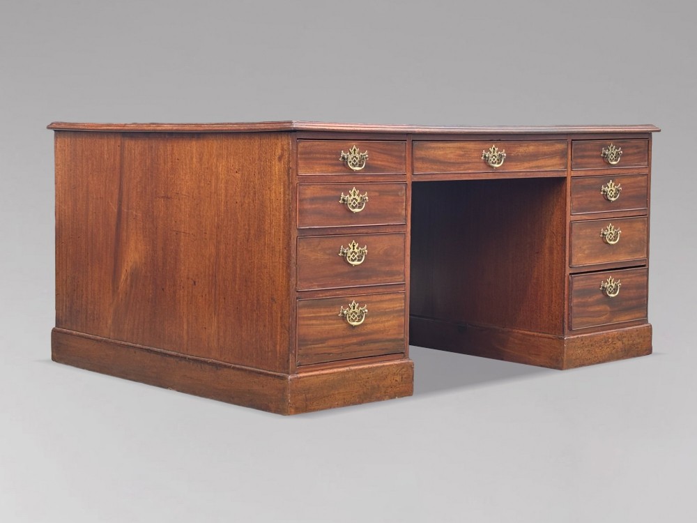 An 18th-century George III mahogany partners desk featuring an inset leather writing surface, brass swan-neck handles, and twin pedestals with stacked drawers. View X