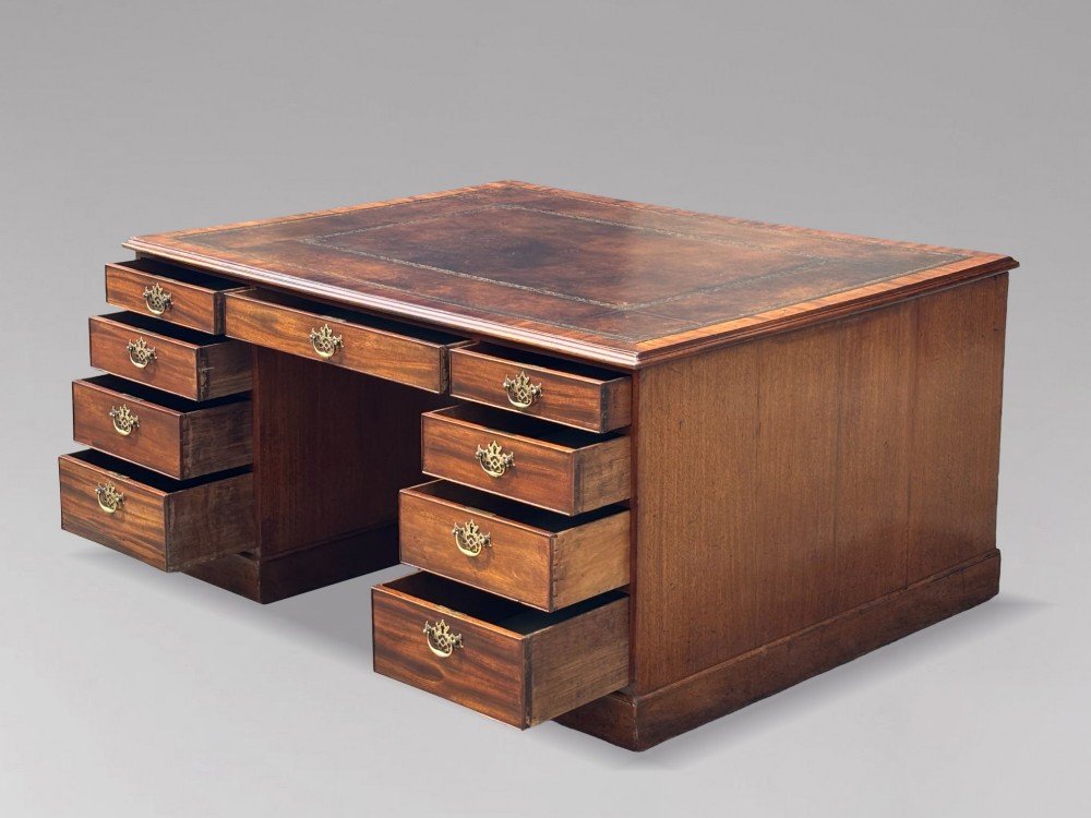 An 18th-century George III mahogany partners desk featuring an inset leather writing surface, brass swan-neck handles, and twin pedestals with stacked drawers. View XI