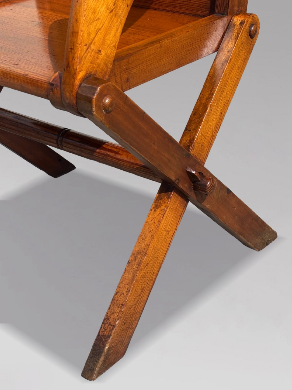 A pair of Victorian pitch pine Glastonbury armchairs featuring sloped armrests, X-frame bases, and pierced trefoil motifs on the back panels. View VII