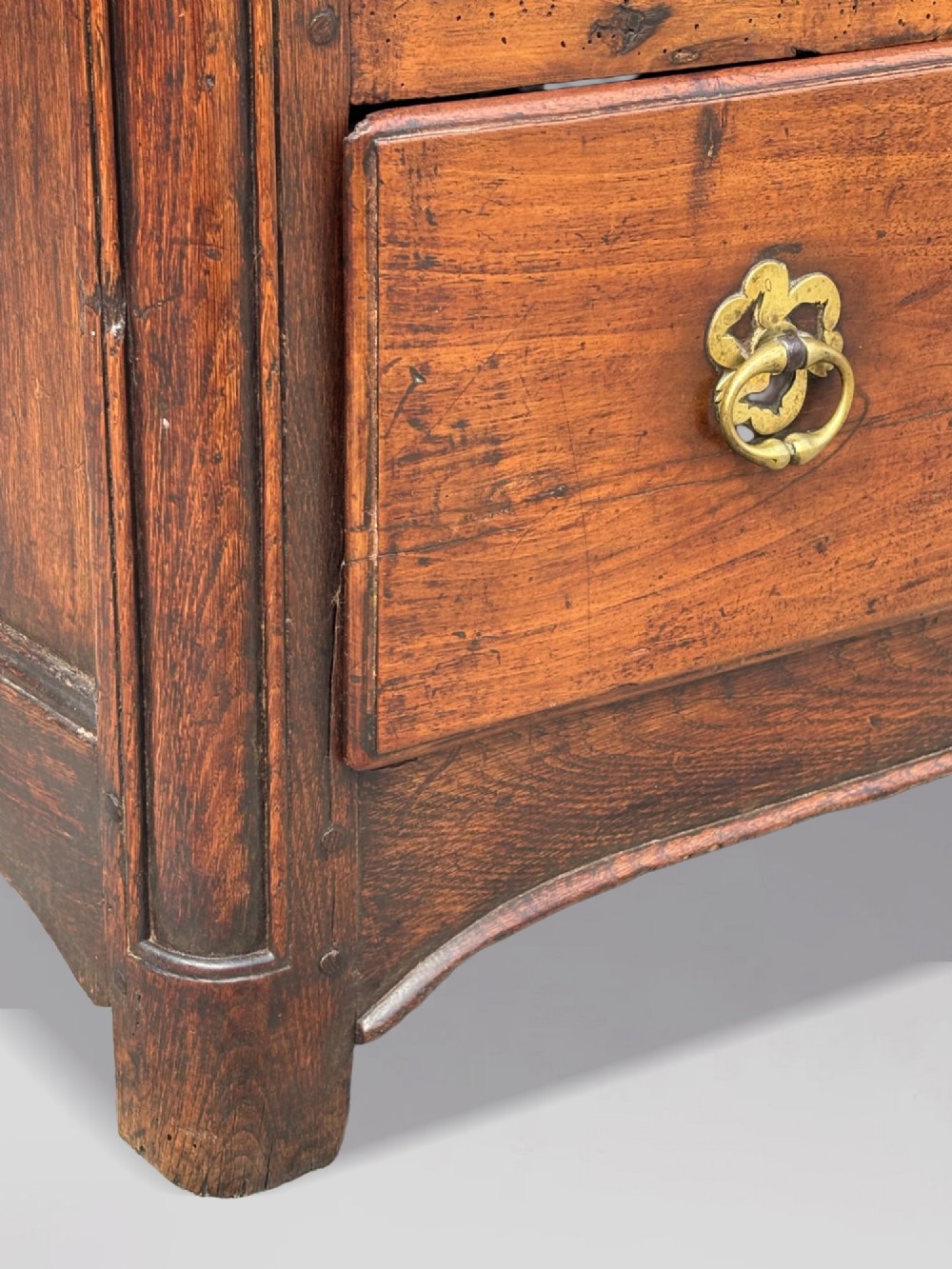 A 17th-century French Provincial walnut commode featuring three long drawers decorated with brass drop handles and central escutcheons. View IV