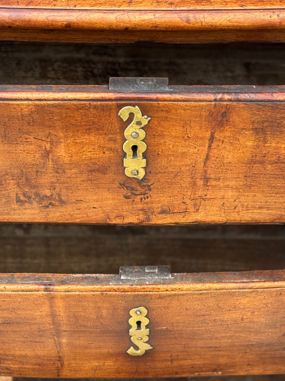 A 17th-century French Provincial walnut commode featuring three long drawers decorated with brass drop handles and central escutcheons. View VI