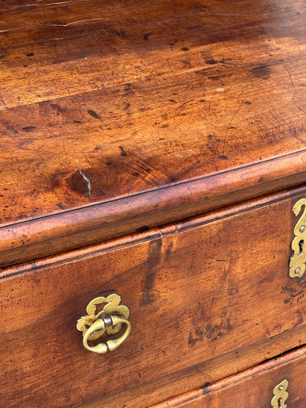 A 17th-century French Provincial walnut commode featuring three long drawers decorated with brass drop handles and central escutcheons. View VIII