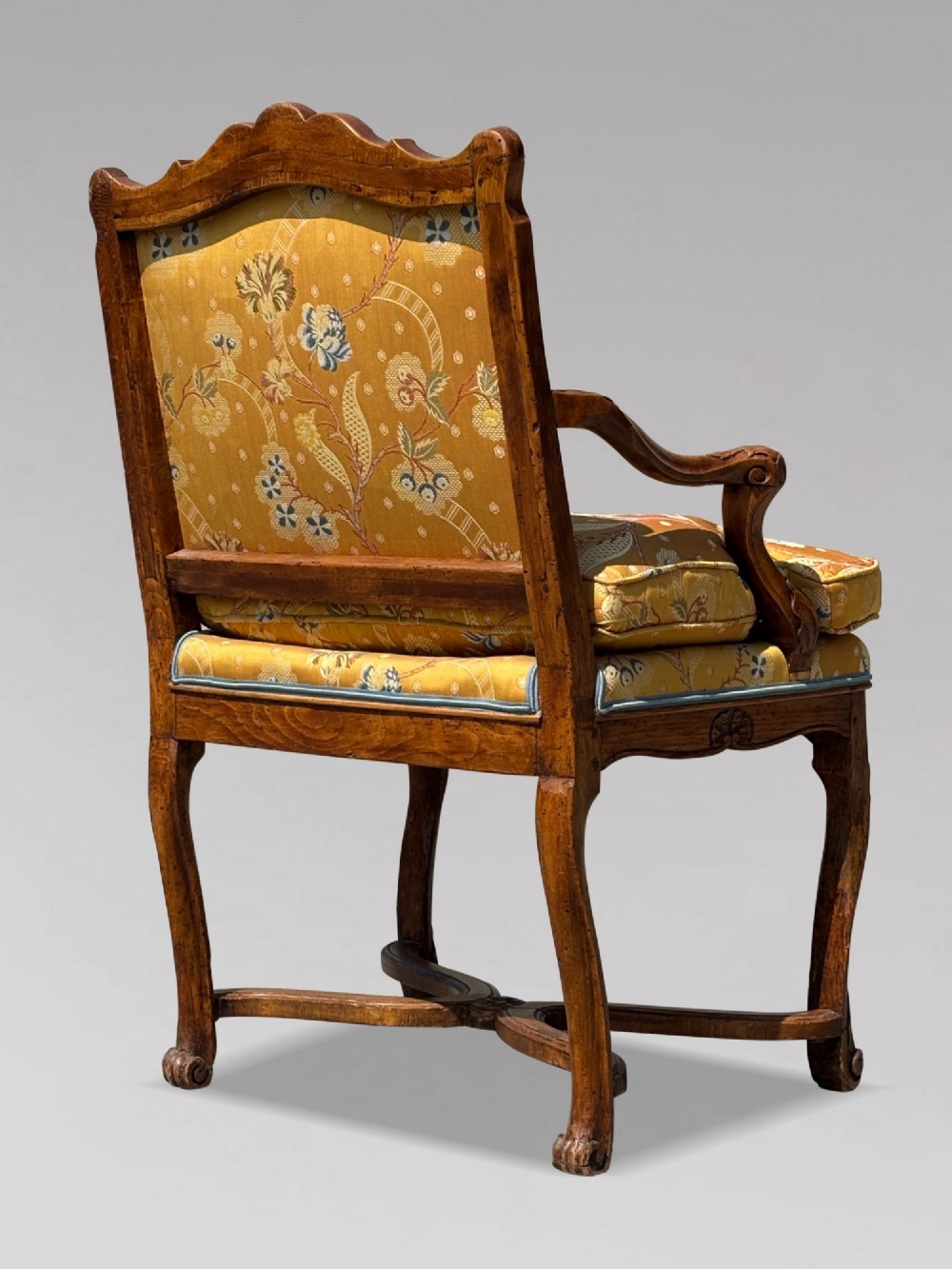 An 18th-century French carved walnut armchair with cabriole legs, an X-form stretcher, and yellow floral upholstered cushions finished with blue trim. View III