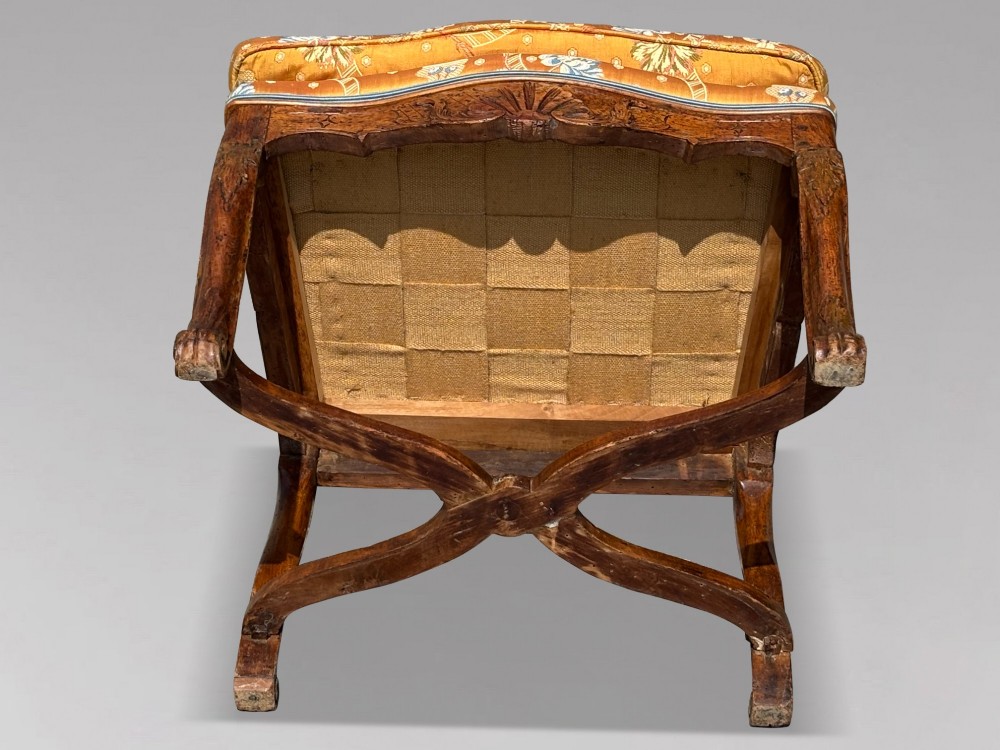 An 18th-century French carved walnut armchair with cabriole legs, an X-form stretcher, and yellow floral upholstered cushions finished with blue trim. View VIII